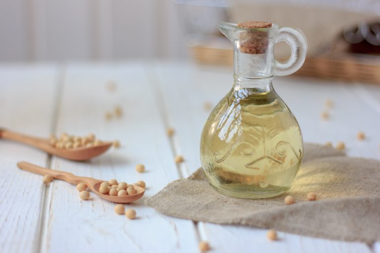 Soy bean oil in glass bottle with soybeans around it